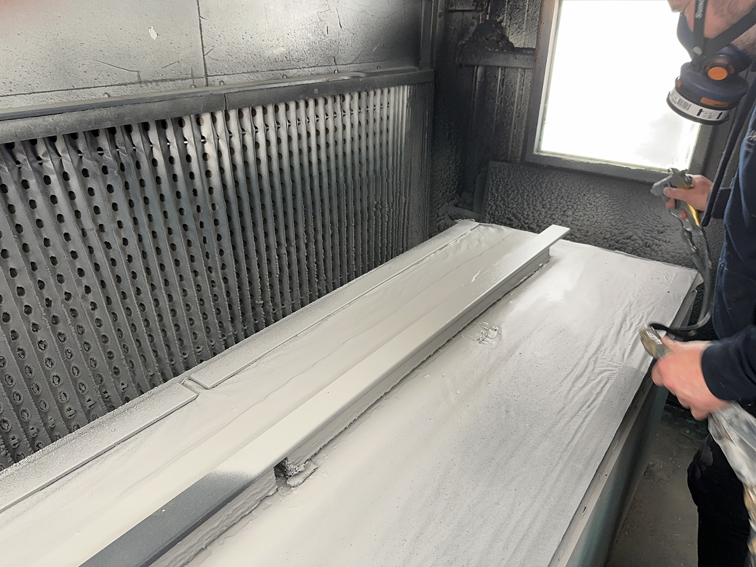 Baker's employee spray painting one of the MTX trims used on the garden buildings