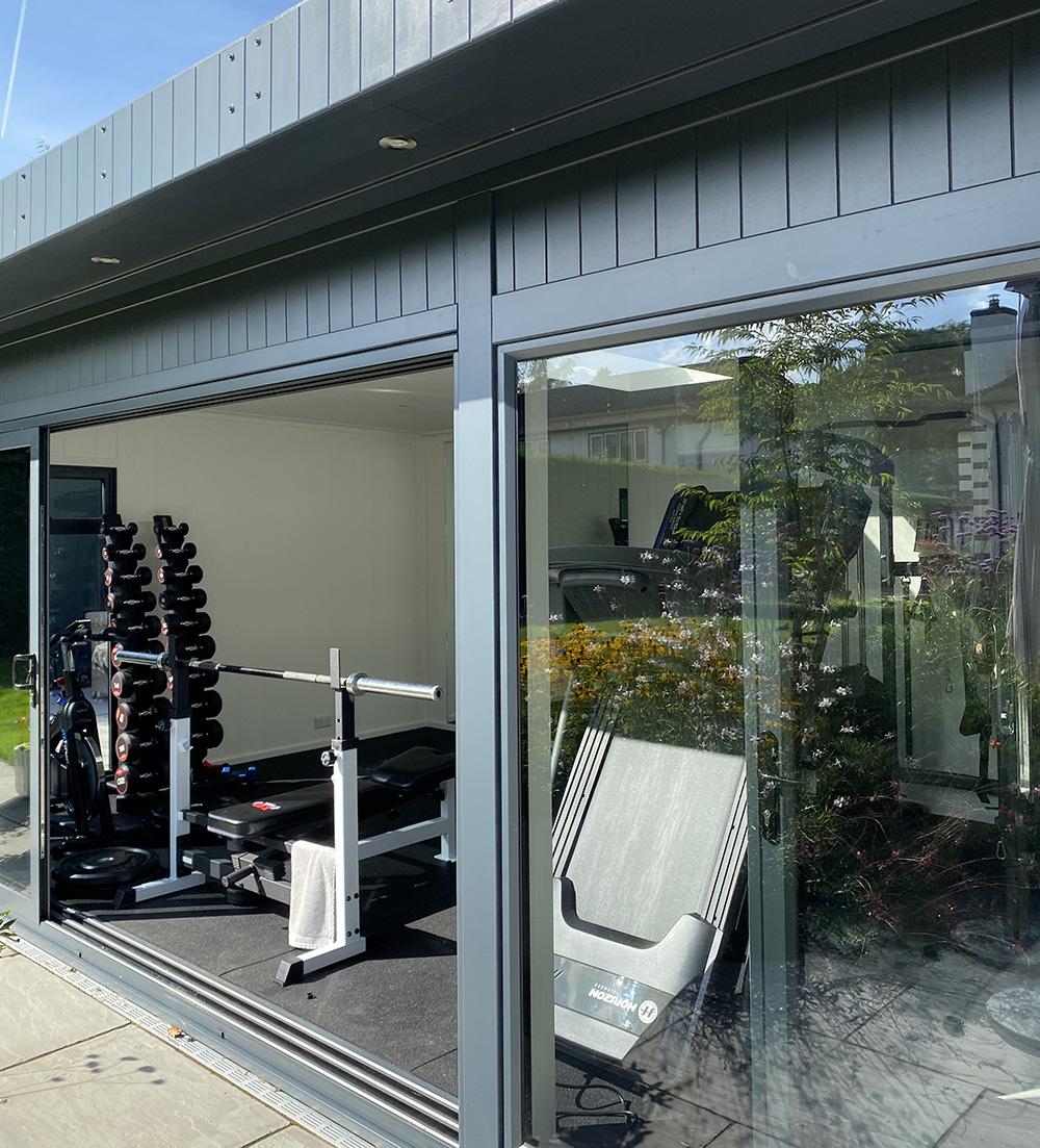 Garden building being used as a home gym with weights and treadmill