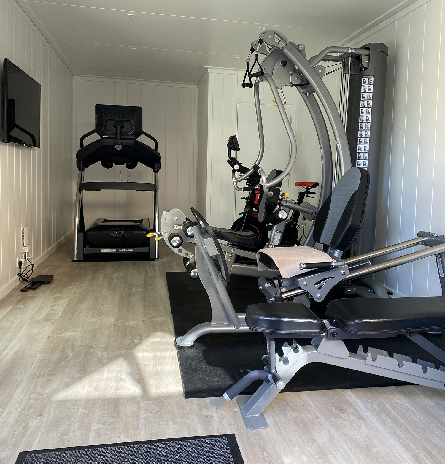 Garden building being used as a home gym showing treadmill and weight machines