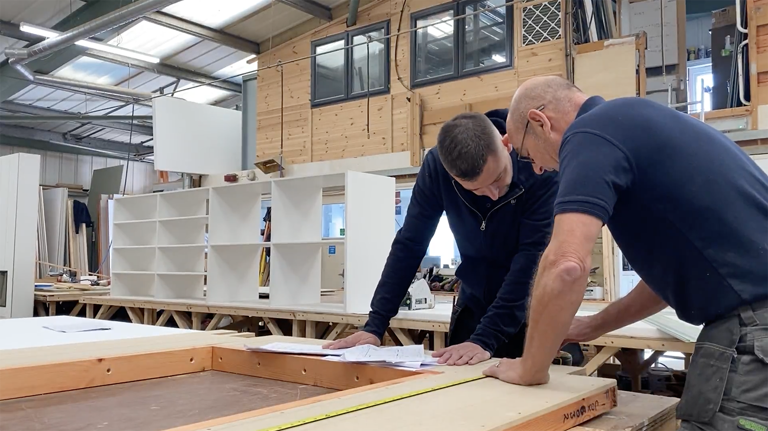 Two of the Baker's team members in the factory looking at garden building measurements 