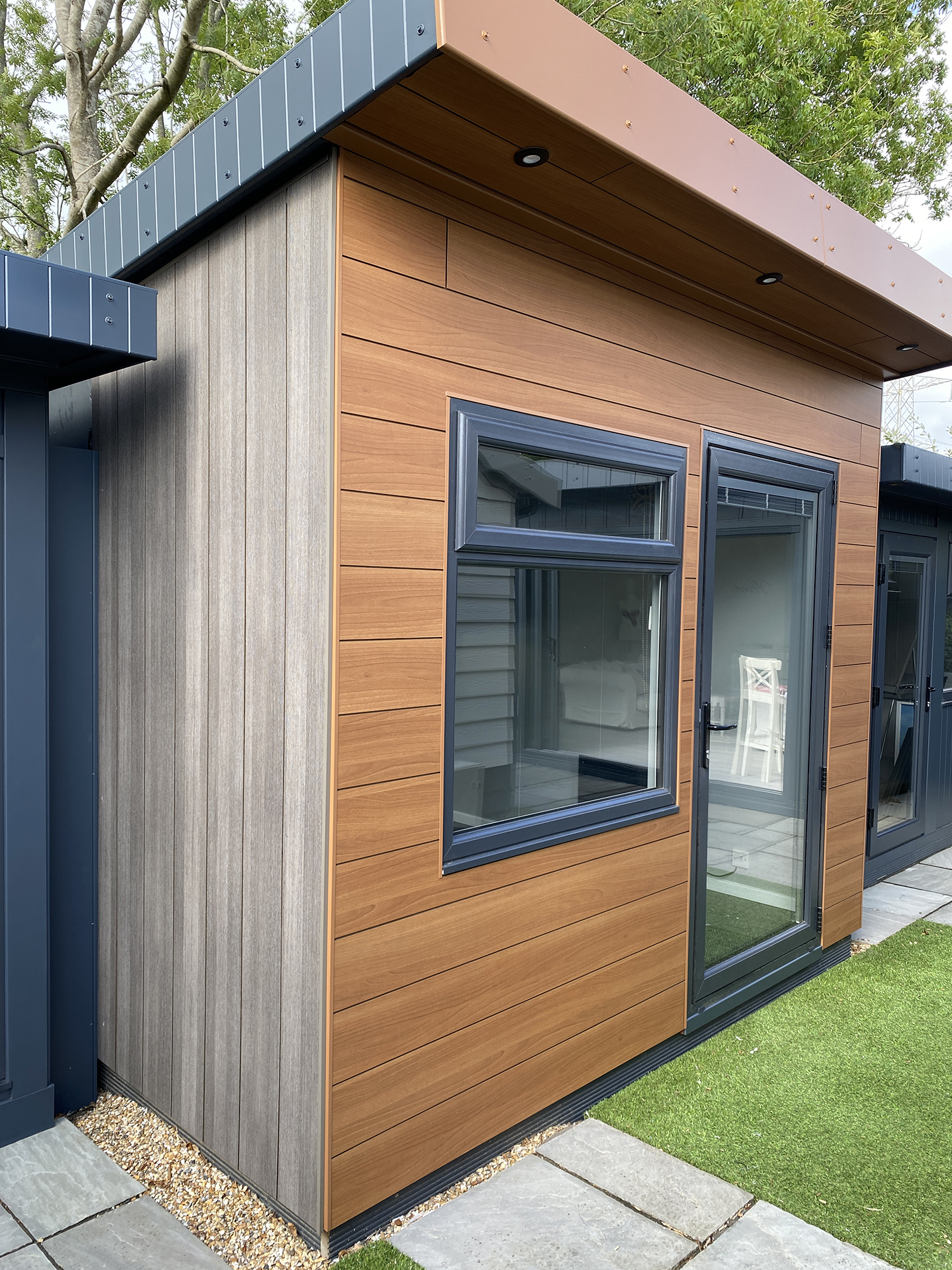 Full image showing the two different Trespa Pura NFC cladding options on a garden building at the Bakers Show Centre
