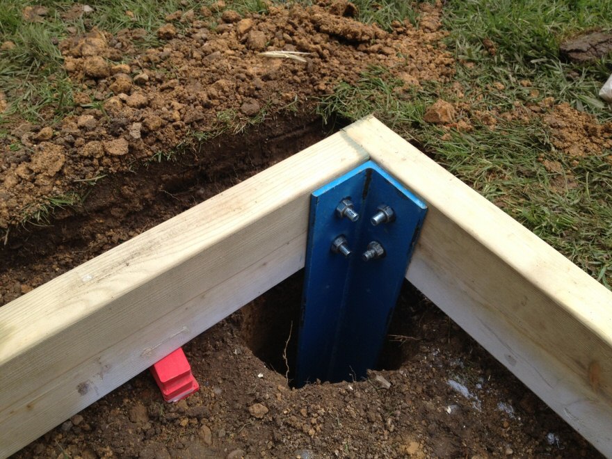 detail of steel sitting in the ground bolted to timber frame