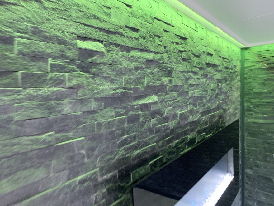 green wall wash against split face tiled wall 