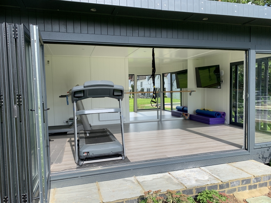 Close-up of the inside of a garden building being used as a gym with treadmill and space to do aerial acrobatics