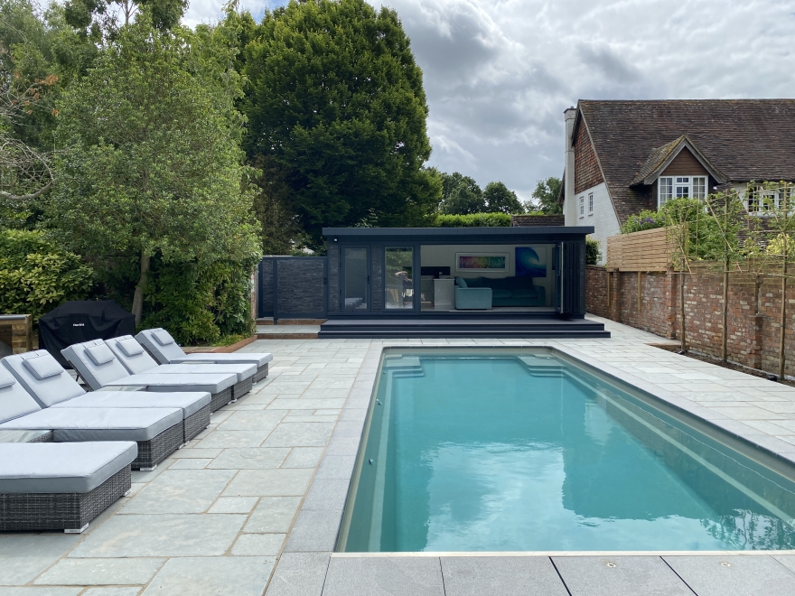This bespoke bi-fold pool-side room features an incredible Howdens kitchen and bathroom with changing room and shower. The perfect pool-side garden building. 
