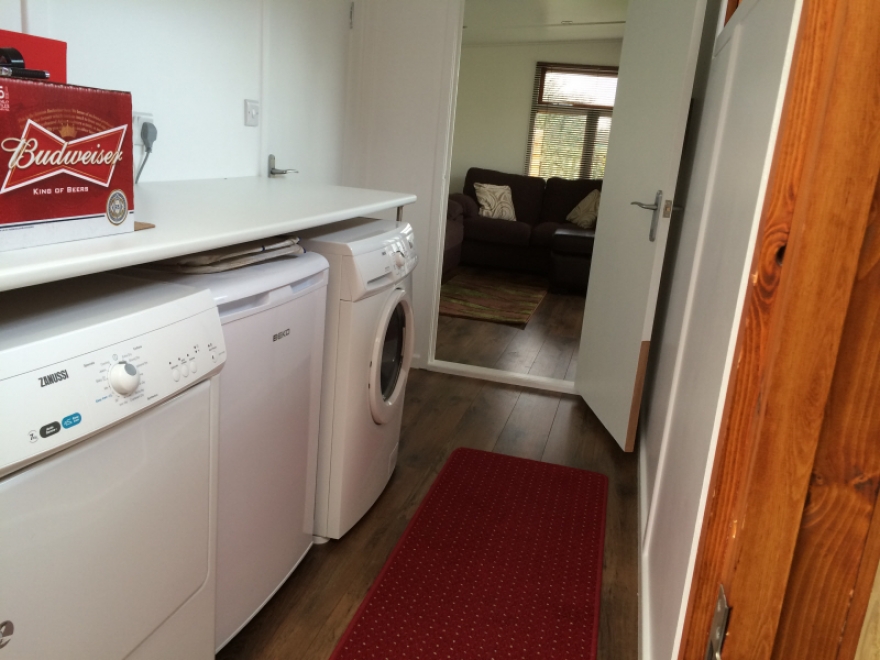 Utility room featuring washing machine, tumble dryer and fridge
